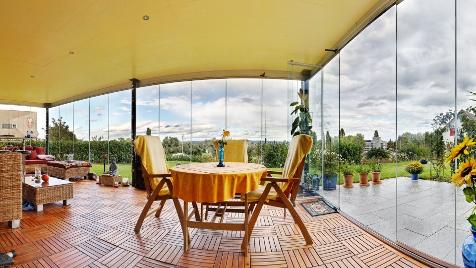 Panorama di una terrazza con vetrata COVER, tavola apparecchiata in giallo e girasoli