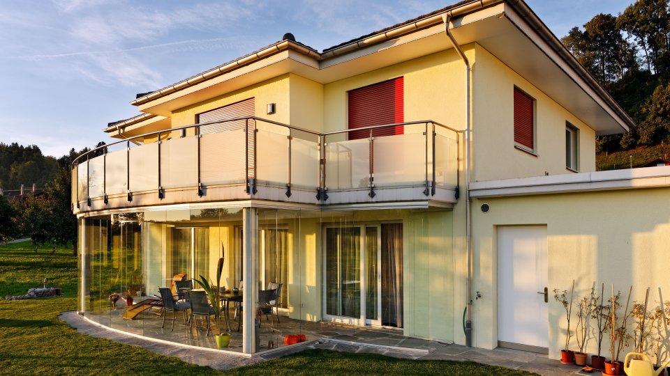 Casa unifamiliare nella luce della sera con vetrata per terrazza COVER arrotondata sotto il balcone