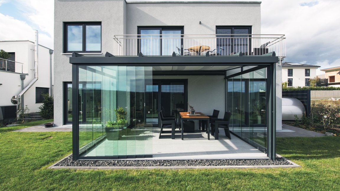 Jardin d’été anthracite avec vitrage coulissant SLIDER et toiture de terrasse ROOFS, coin repas devant une maison moderne