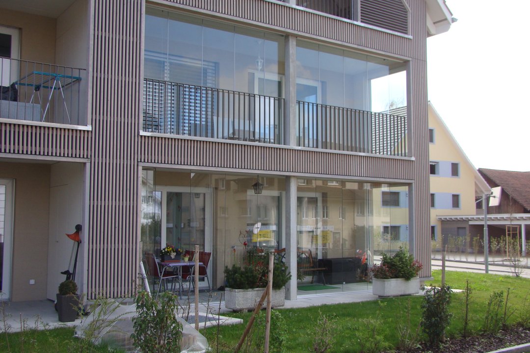 Immeuble avec balcon vitré à l’étage et terrasse vitrée au rez-de-chaussée